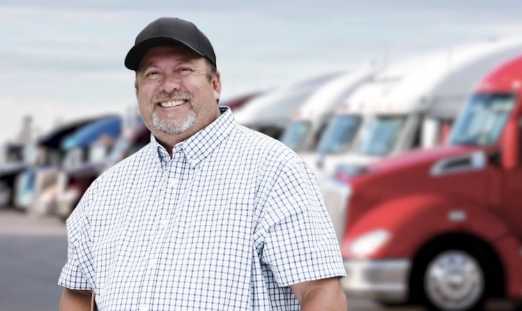 Conductor de camión sonriendo a la cámara después de inscribirse en un plan de protección de boletos CDL Pro-Driver de TVC y recibir la mejor tarjeta de combustible para camioneros