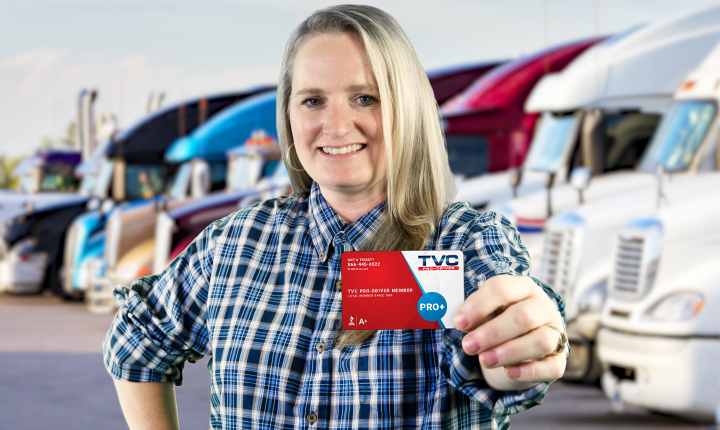 A female truck driver holding up her TVC Pro-Driver fuel card, the best fuel card for truckers that is accepted at more than 15,000 locations