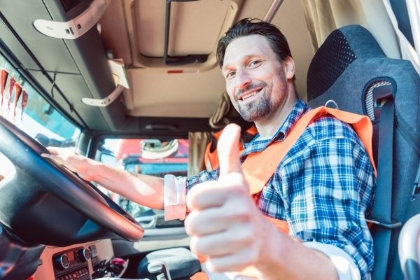 Camionneur avec protection TVC Pro-Driver CDL et la meilleure carte de carburant pour les camionneurs souriants et donnant un coup de pouce à la caméra
