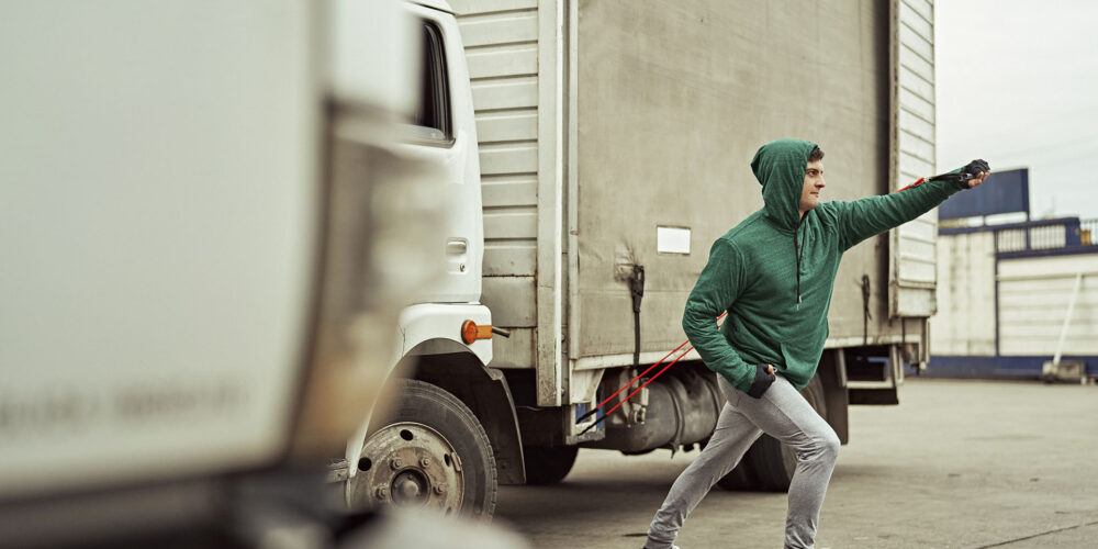 Full length view of Caucasian transportation worker in hooded shirt and sweat pants building upper body strength to help endure long distance road trips.